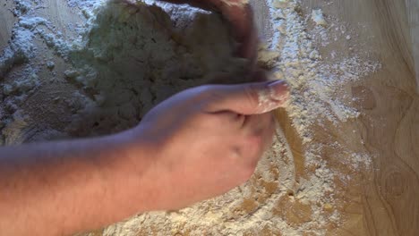 dough being kneaded on a wooden work surface for baking