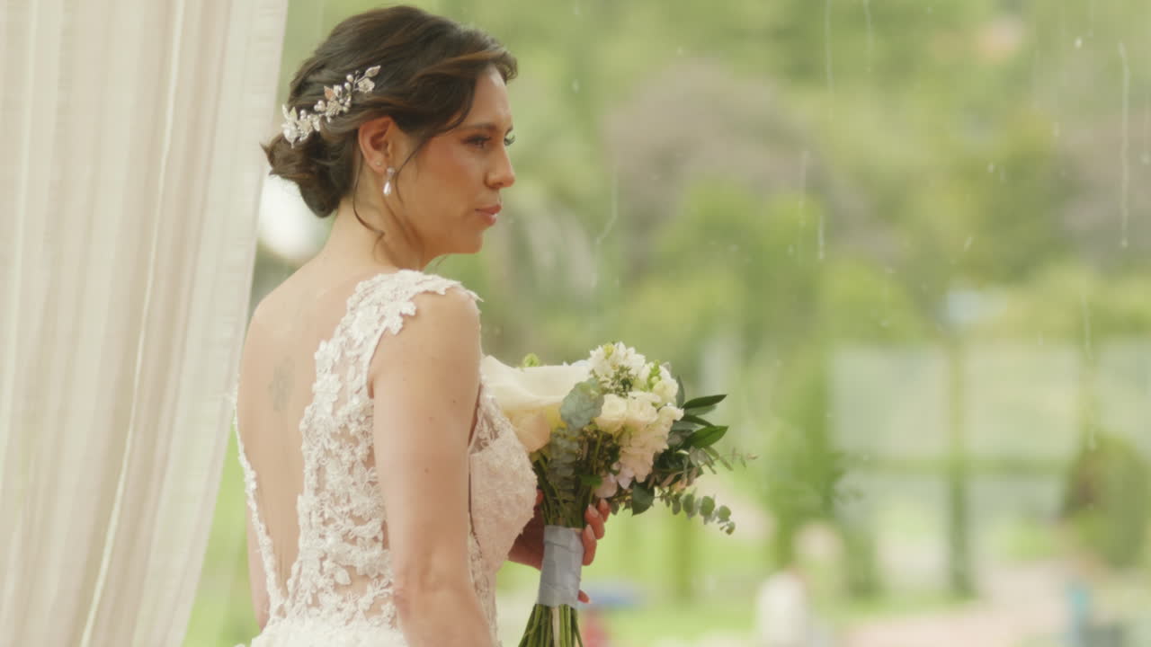 Medium shot of a bride walking with a bouquet of flowers, wearing a lace dress as she heads to the ceremony.