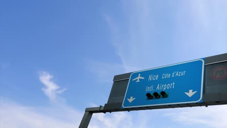 airplane passing over nice airport sign