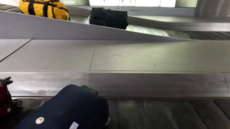 red suitcase and black bag on airport conveyor