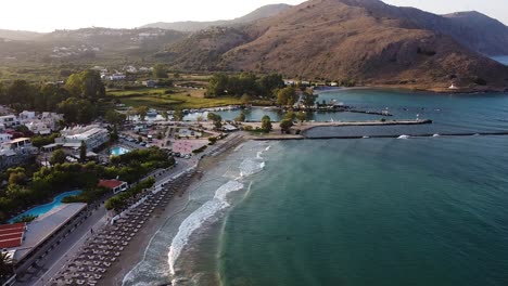 sea waves and dusk over small crete township, aerial view