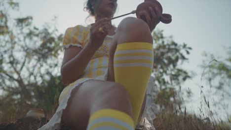 low-angle slo-mo shot of an attractive young indian woman in a yellow ruffle dress, painting broken pottery shards, shallow depth of field