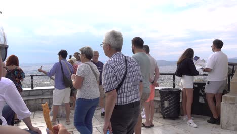 crowd of tourists enjoying views over athens from lycabettus hill