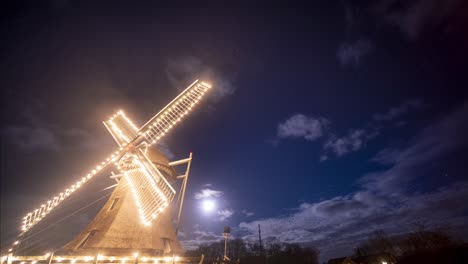 molino de smock brillantemente iluminado por la noche con nubes en movimiento en el fondo