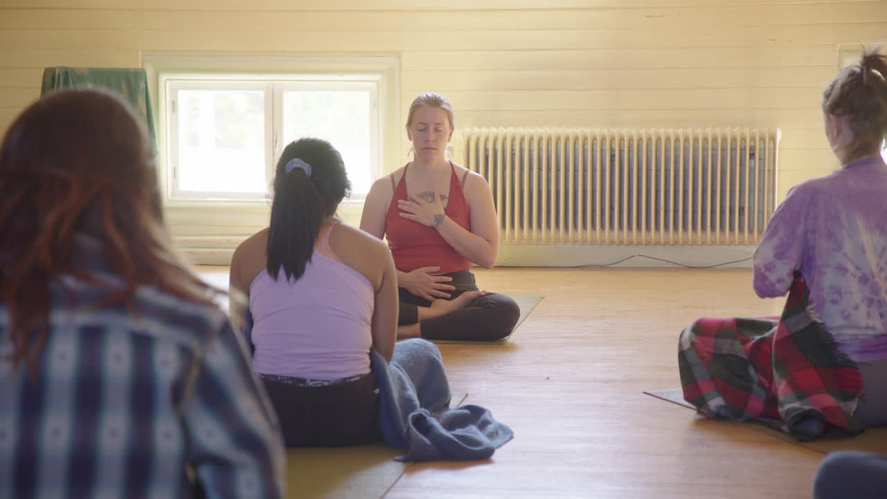 Åndedrætsøvelse ledet af kvindelig yogainstruktør med hænderne på maven og hjertet