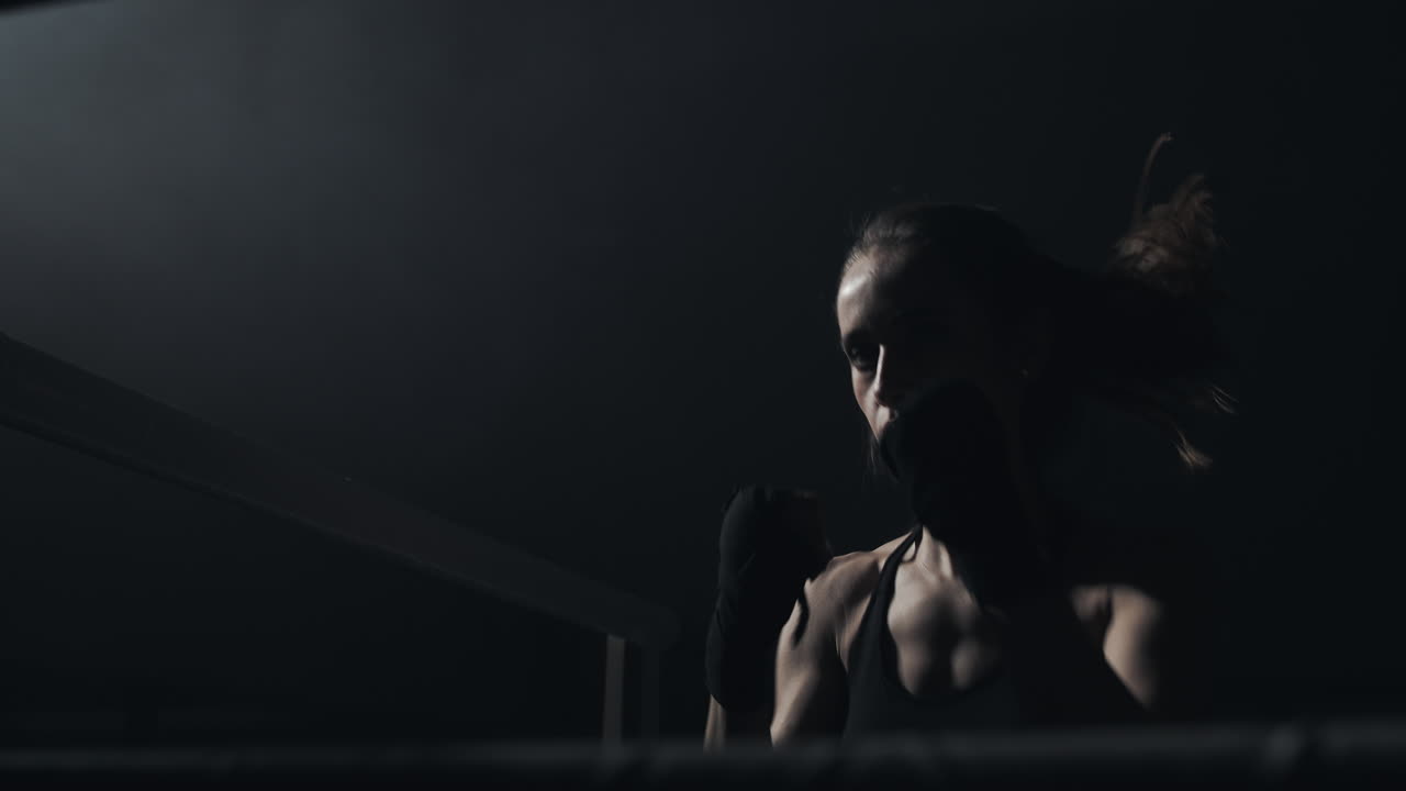 Female Boxer Training in a Dark Ring