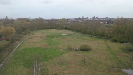 Approaching-drone-shot-showing-a-hiking-trail,-camping-ground-and-the-town-of-Leicester-Riverside-in-the-background-of-a-countryside-in-United-Kingdom