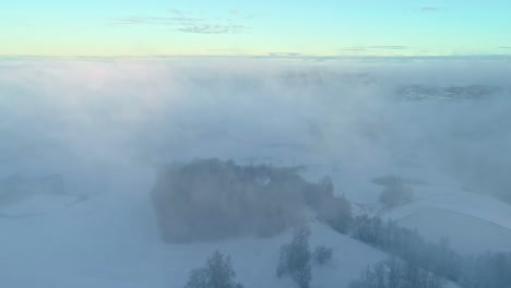 descending-drone-flight-through-low-hanging-clouds-to-a-small-peninsula-in-a-winter-landscape