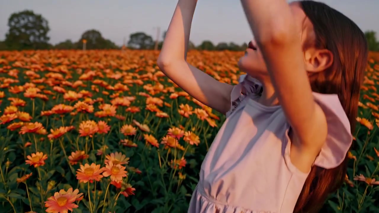 Giovane ragazza che allunga la mano in un vivace campo di fiori al tramonto