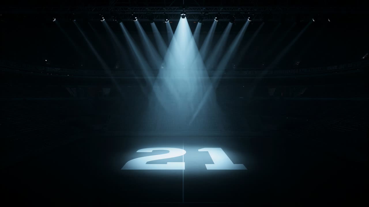 Accensione del faretto a soffitto, struttura del palco che proietta il numero 21 in grassetto sul pavimento dell'arena, a indicare l'evento