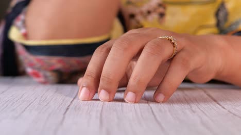 woman's hand with ring on wooden table