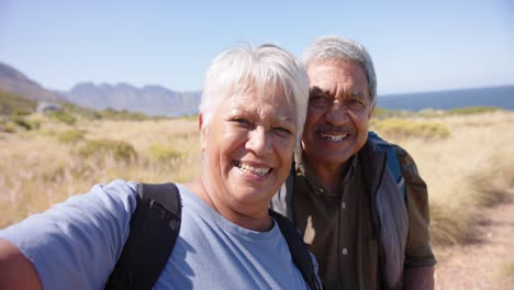 Retrato-De-Una-Feliz-Pareja-Birracial-De-Ancianos-En-Las-Montañas-Abrazándose,-En-Cámara-Lenta