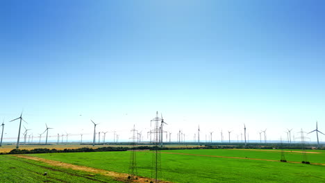 going up over the green plantation in the countryside. multiple wind mills produce clean energy in the fields