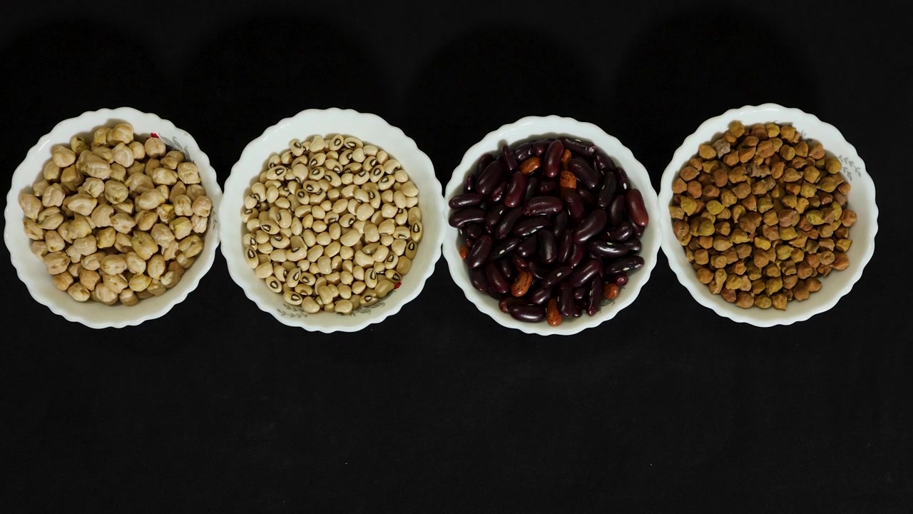 healthy protein rich pulses assortment displayed in white bowls on dark backdrop