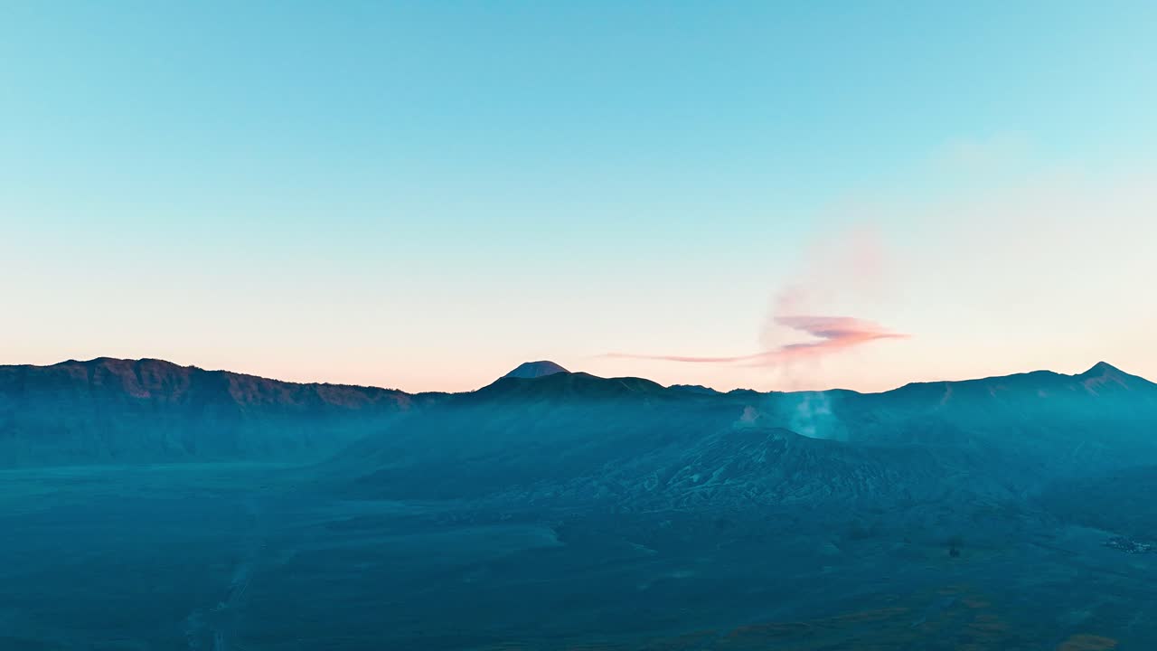 Hyperlapse drone capture of Mount Bromo’s volcanic caldera at sunset in East Java, Indonesia—lit in a fiery glow as clouds and smoke swirl above the ancient volcanic landscape