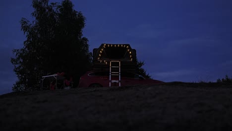 Low angle view of rooftop tent lit with warm string lights at night in Europe