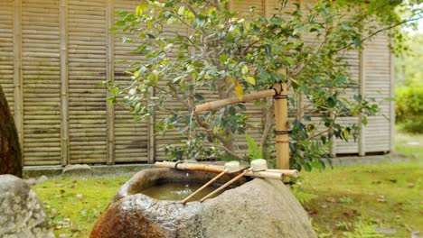 Slide-shot-of-water-pouring-out-of-a-bamboo-in-Kyoto,-Japan-4K-slow-motion