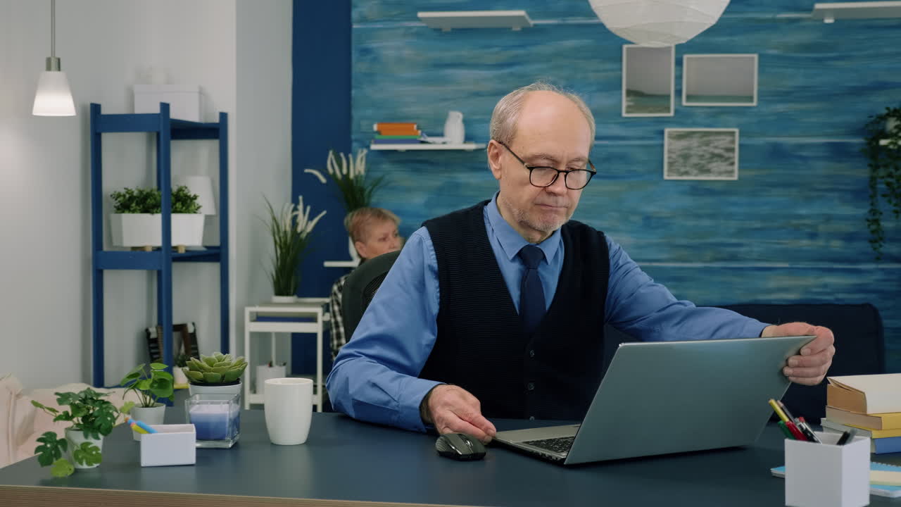 Senior remote businessman opening laptop and reading reports