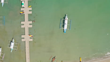 aerial view of outrigger boats and floating dock on a tropical coastline