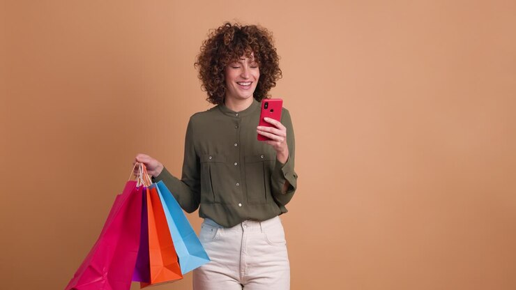 Donna entusiasta con borse della spesa e cellulare in studio
