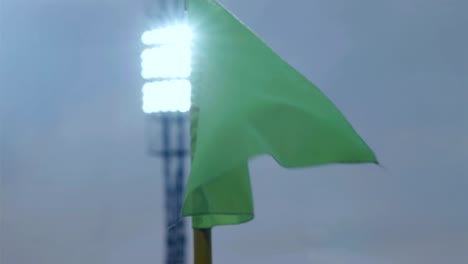 corner flag post blown by wind on soccer stadium at night, stadium lights in the background