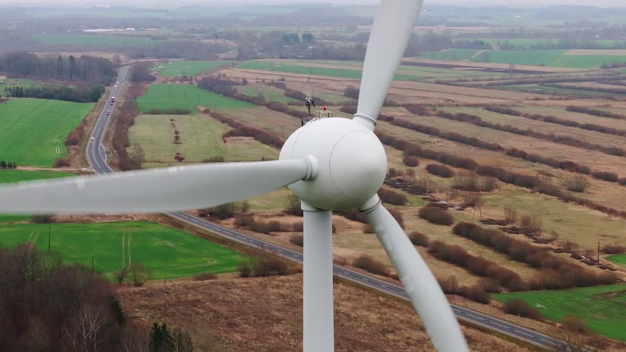 Dynamic aerial footage of a wind turbine spinning in an open countryside