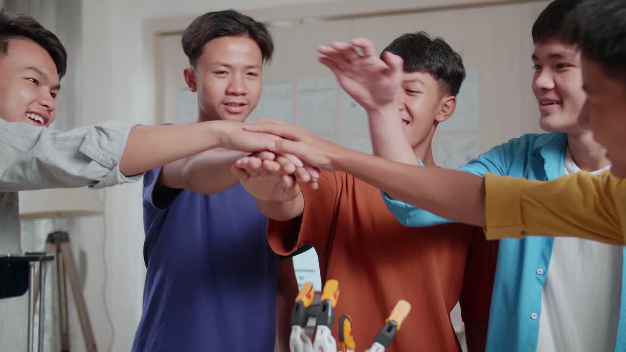 노트북과 3d 프린팅을 가진 젊은 아시아 소년 그룹이 집에서 사이보그 손을 작업하는 동안 함께 손을 잡고 있습니다.