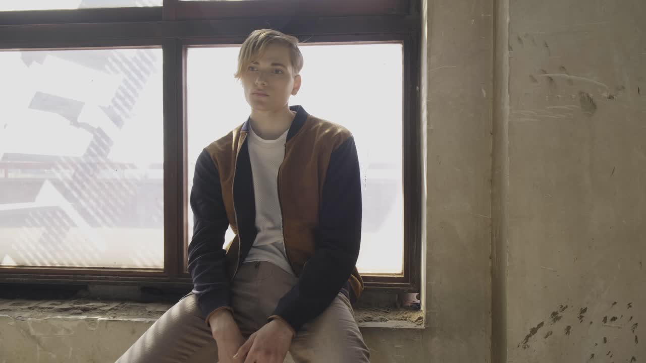 ⁇ 은 방의 창문 근처에 앉아 있는 젊은 남자