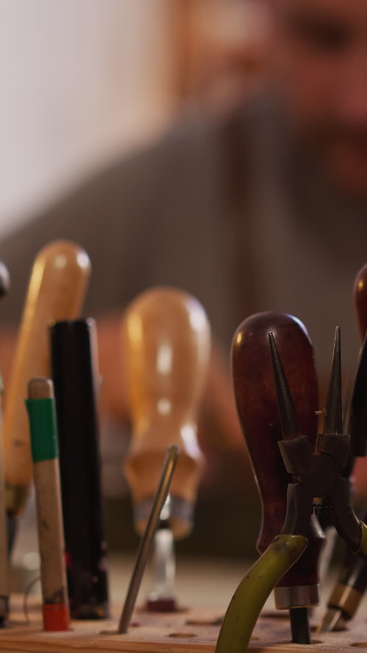 Worker hand takes cutter for leather from wooden rack in workshop closeup. Manual processing of craft material. Instrument kit in manufacturing studio