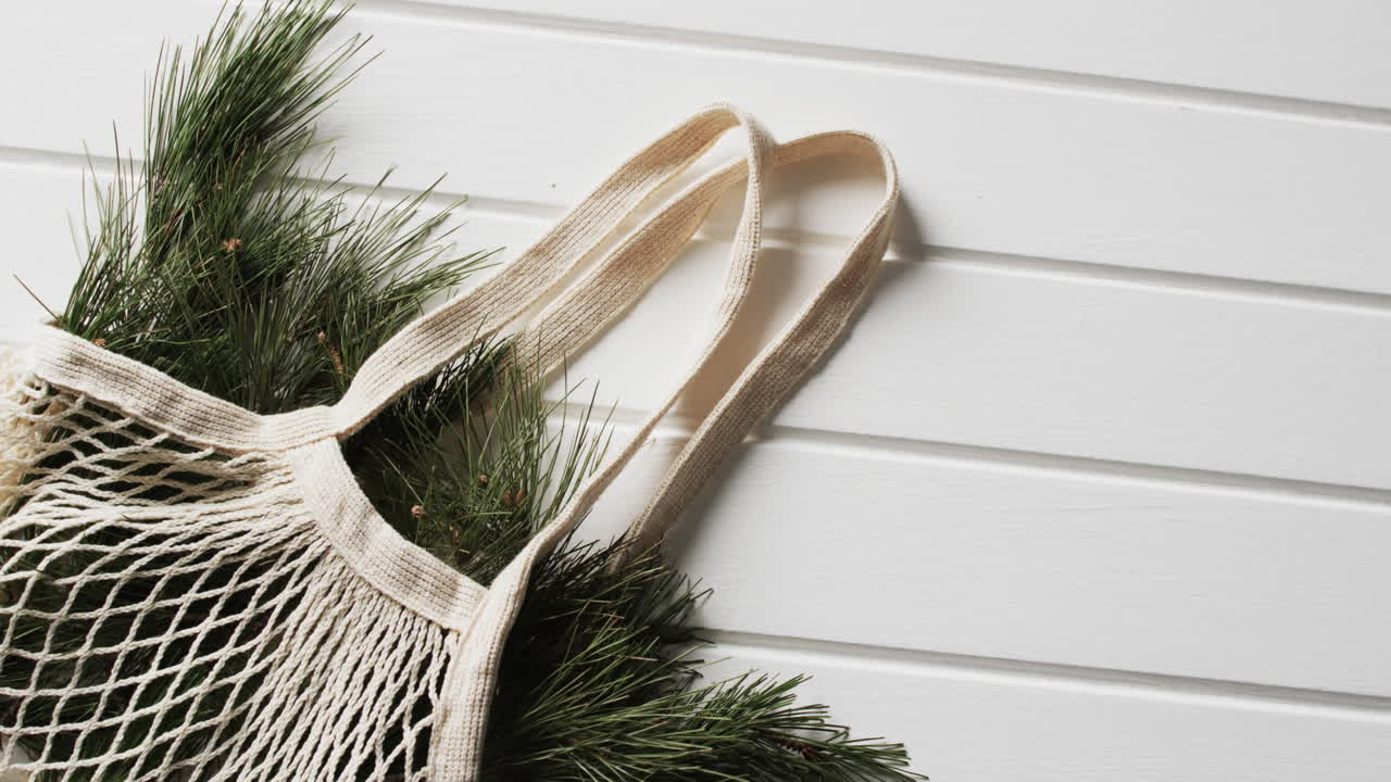 색 배경에 크리스마스 소나무 가지와 복사 공간을 가진 네트 가방의 비디오