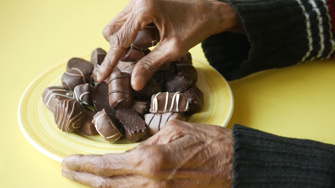 manos de ancianos comiendo chocolates