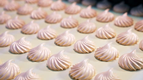 pink creamy zephyrs production on the food factory. savory desserts moving along conveyor belt close up. blurred background.
