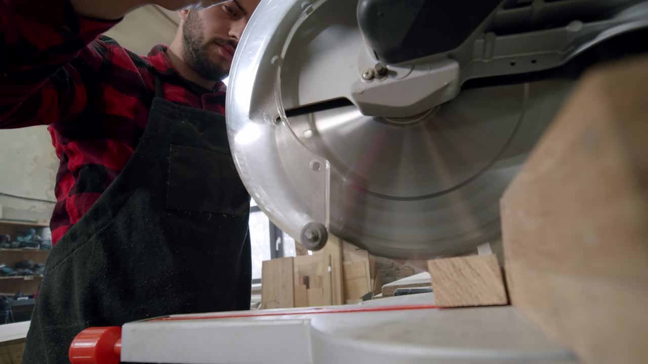 movimiento lento de cerca. el maestro corta una tabla de madera con una sierra circular en el taller de carpintería de un pequeño fabricante de muebles. v2