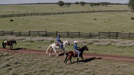 cowboys riding horses on a ranch