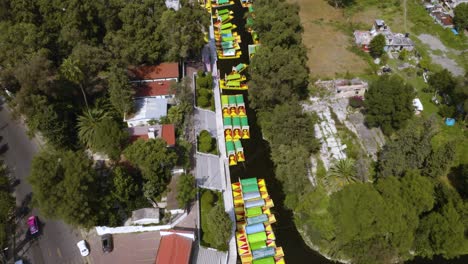 drone flies above xochimilco canals full of colorful trajineras near mexico city