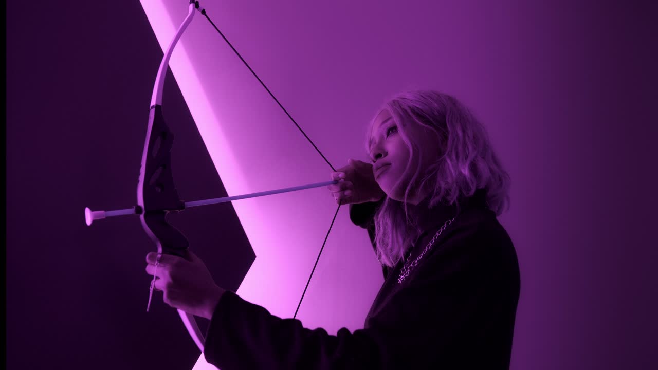 niña africana negra mujer hembra dispara con arco neón magenta rosa luces