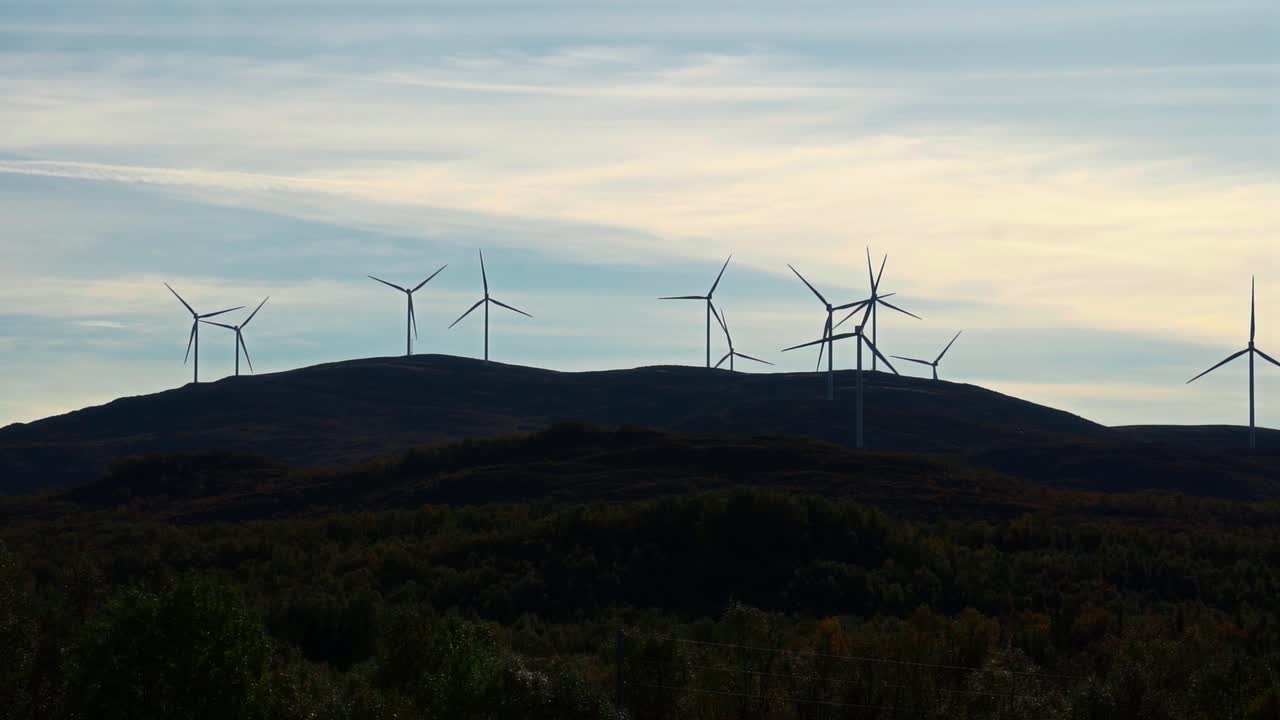 A wind farm on Vestarelen with turbines on a hillside, set against a sky at dusk