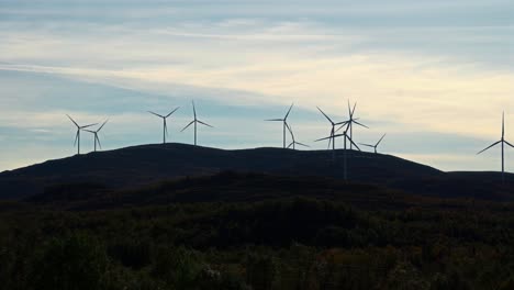 a wind farm on vestarelen with turbines on a hillside, set against a sky at dusk