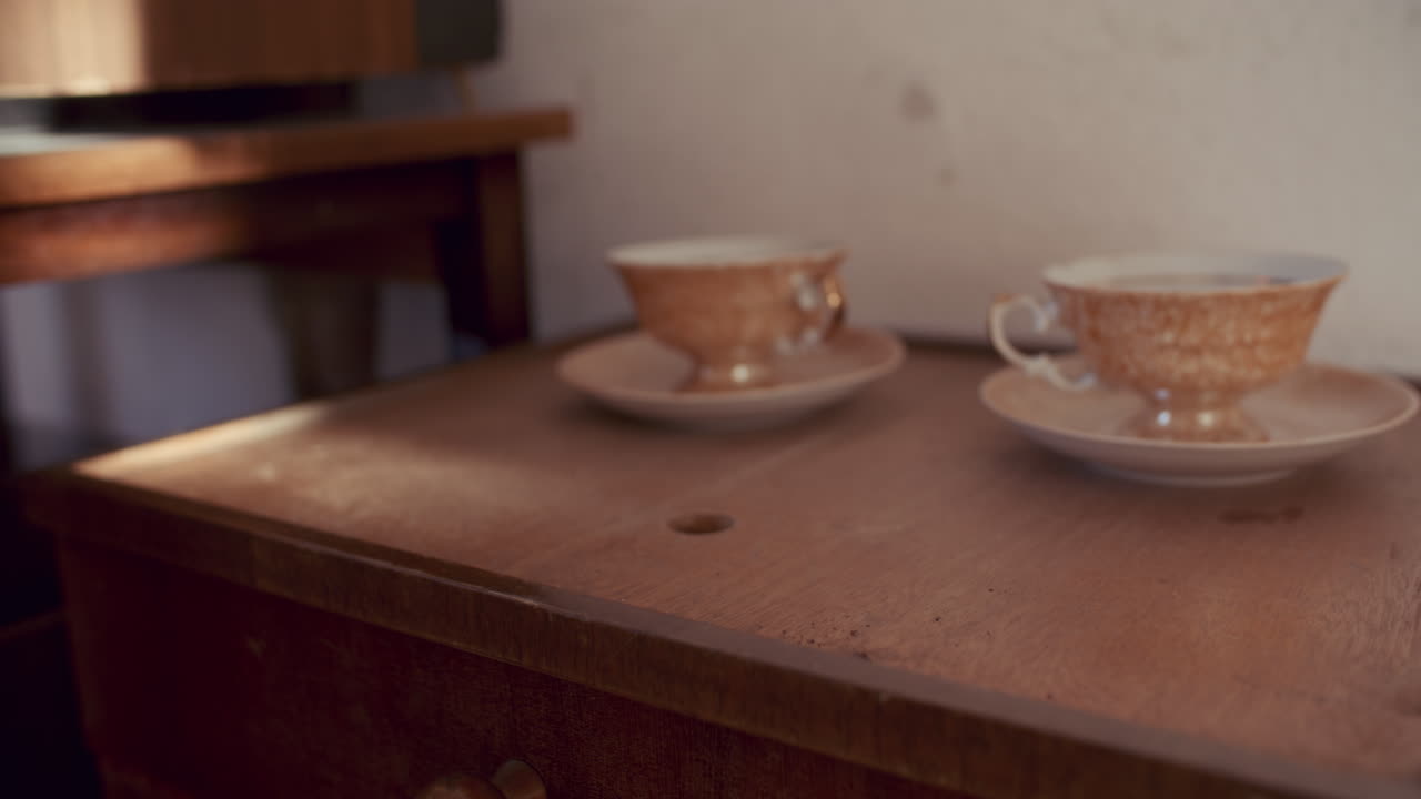 Woman picking up a letter on a wooden nightstand with teacups