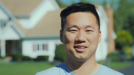 portrait of a young asian man smiling looking at the camera against a blurred background at home