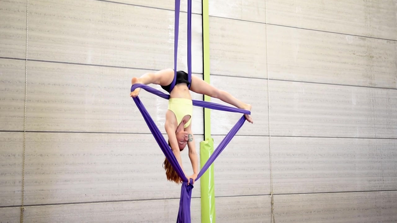Giovane donna dai capelli rossi che fa acrobazie ginniche aeree.