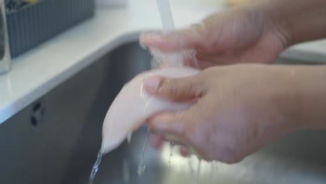 washing chicken breast in a kitchen sink