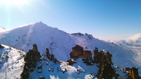 flying at bird's eye height over snowy cliffs in sunny weather