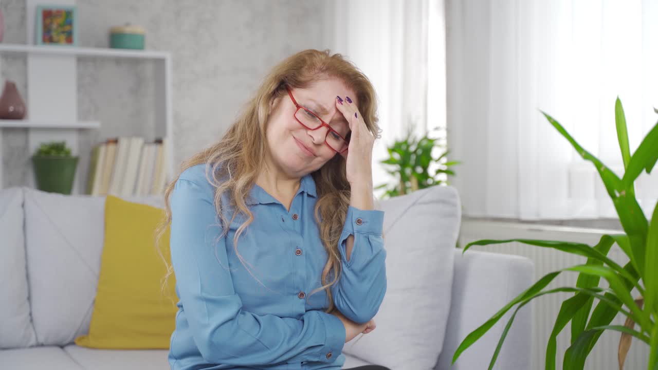 una mujer madura tiene dolor de cabeza.