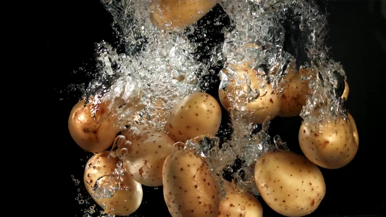 Patate fresche che cadono nell'acqua con bolle al rallentatore