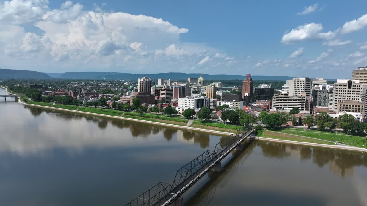 Aerial flyover Susquehanna River and Walnut Street Bridge in Harrisburg. Downtown complex and buildings in background. Approaching shot. Sunny day in summer. Pennsylvania, United States