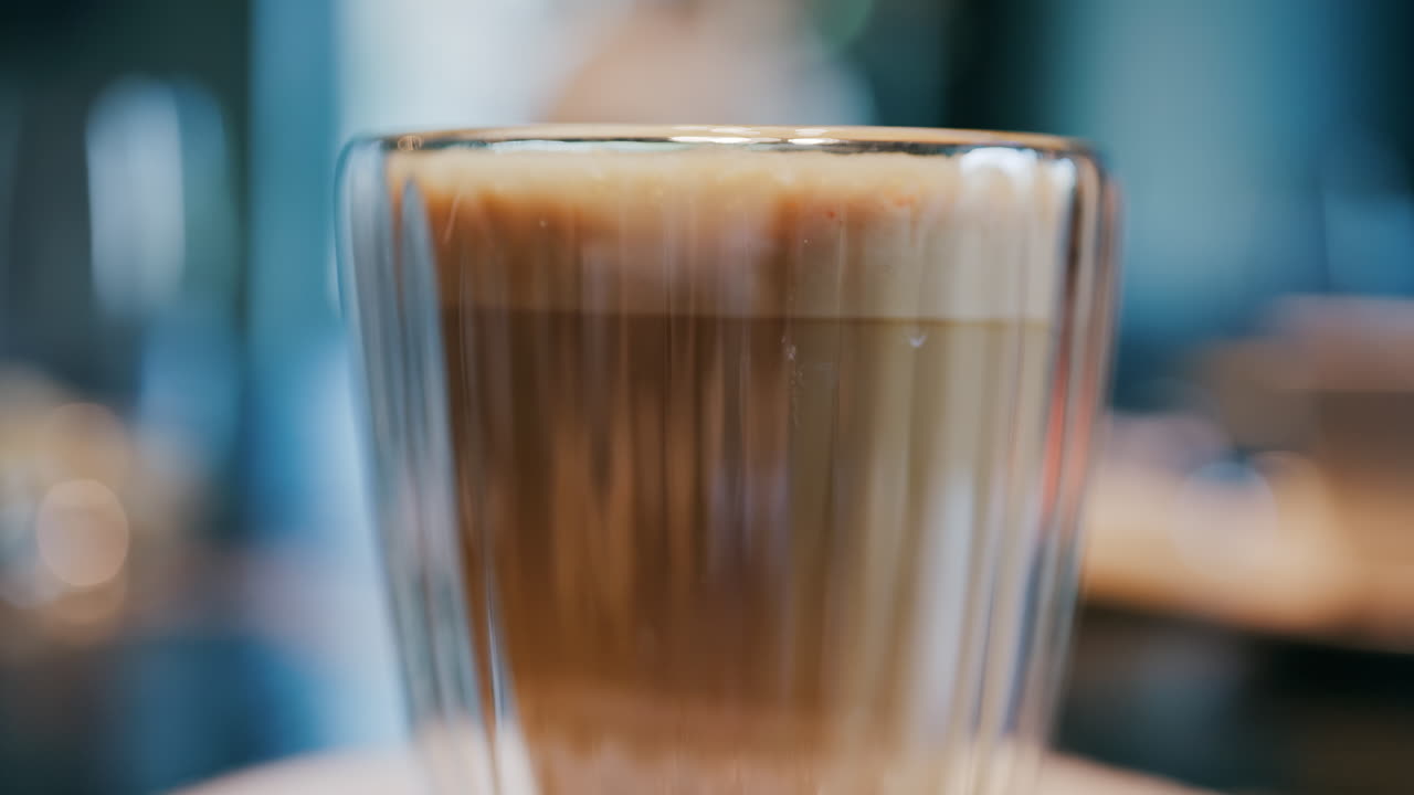 Close up of a glass cup with a latte at a cafe