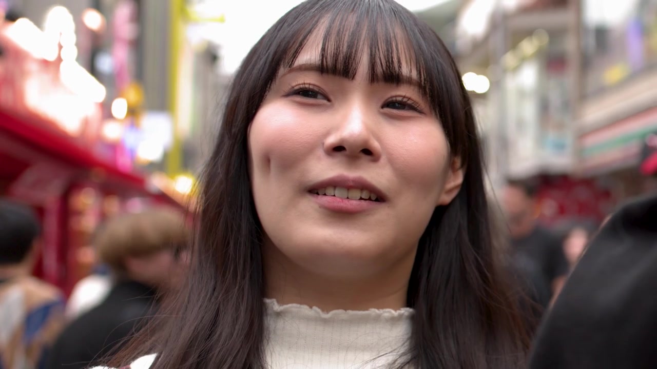 東京繁華購物區中，一位微笑的亞洲女性正在交談的特寫