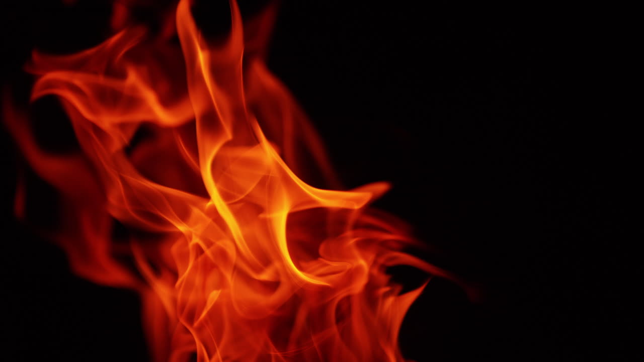 Red fire flames moving in the wind. Blaze in the darkness isolated. Close up.