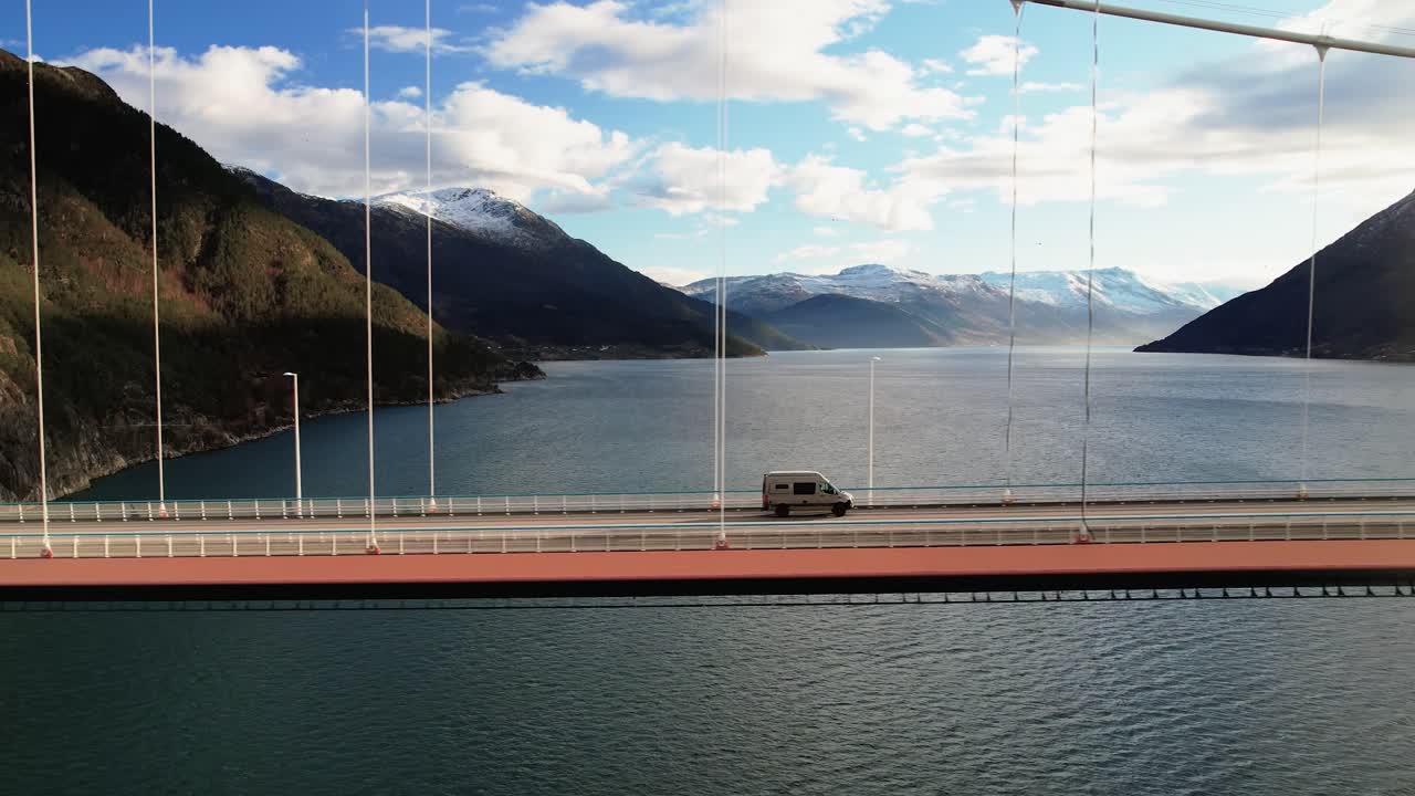 화려한 하늘 아래 조용한 피오르드 위의 경치 좋은 산 다리를 건너는 밴